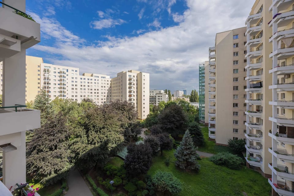 A view from the building showing nearby residential buildings and greenery on a sunny day.