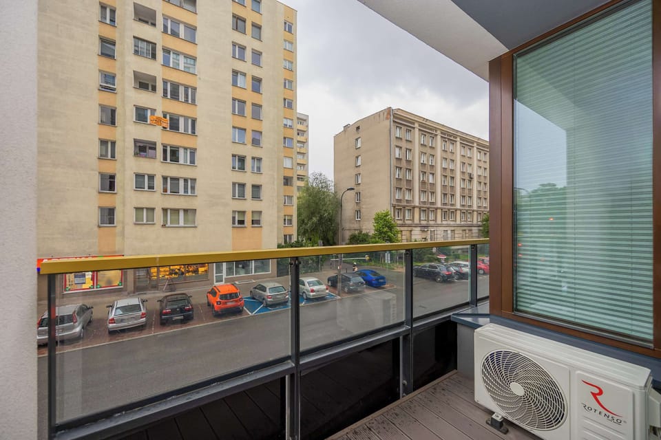 A balcony view overlooking nearby apartment buildings and a quiet street. The outdoor space is small but functional, suitable for fresh air and relaxation.