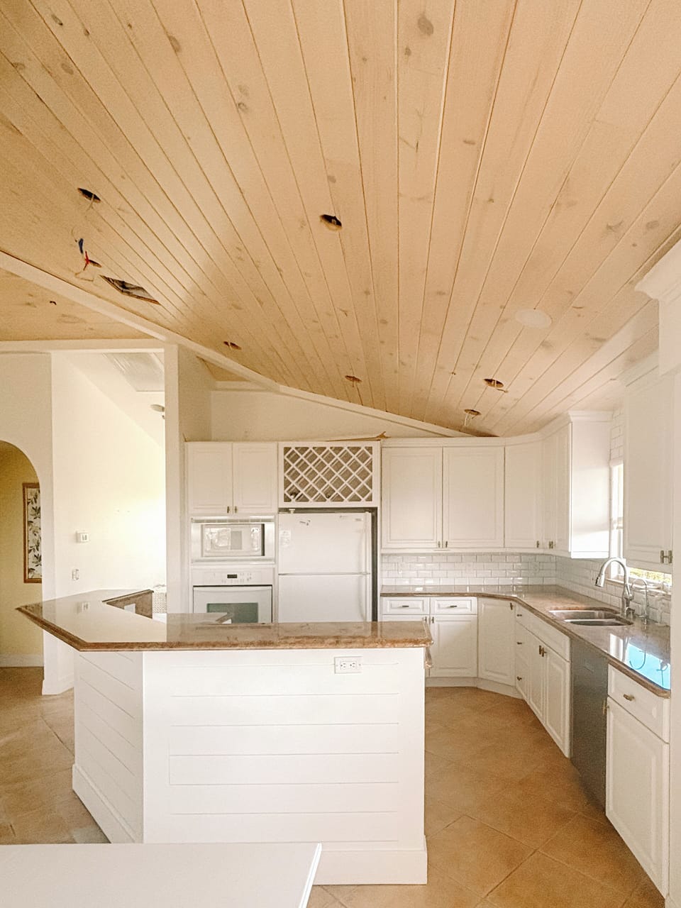 Freshly painted living room/kitchen with new, planked ceiling.