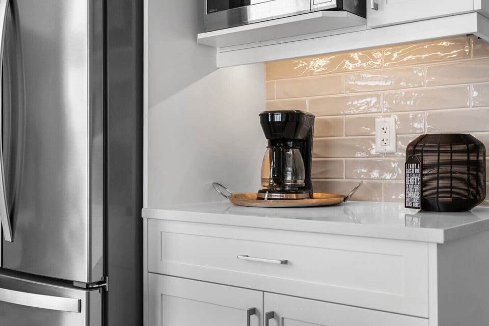 Kitchen features stainless refrigerator, microwave, and drip coffee maker