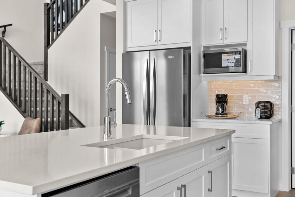Fully equipped kitchen with island sink, refrigerator, microwave, and dishwasher