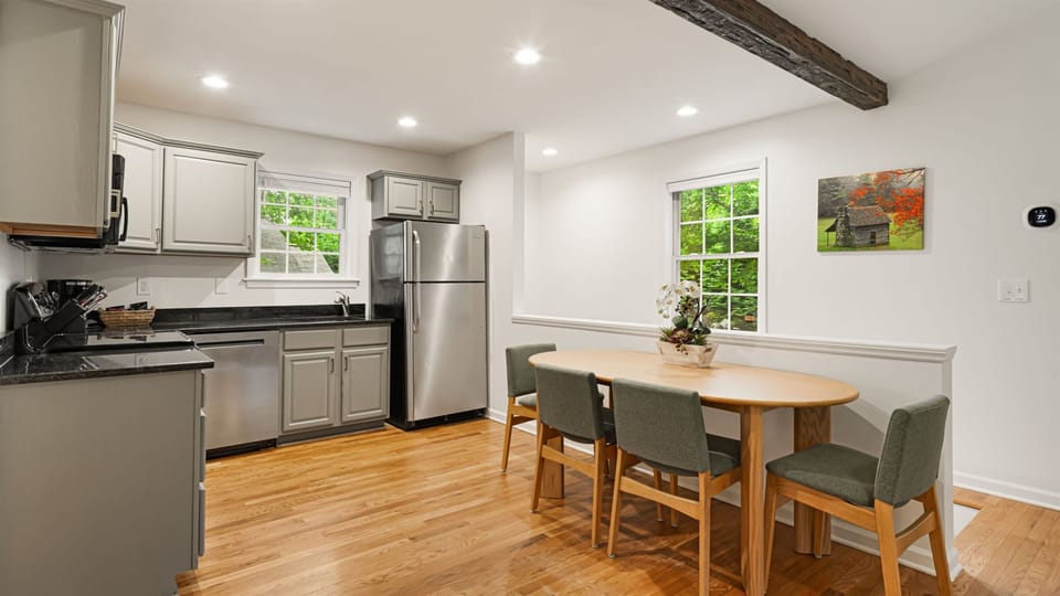 Kitchen and dining — stainless appliances, 6-person table, dark granite counters. Fully equipped for group cooking.