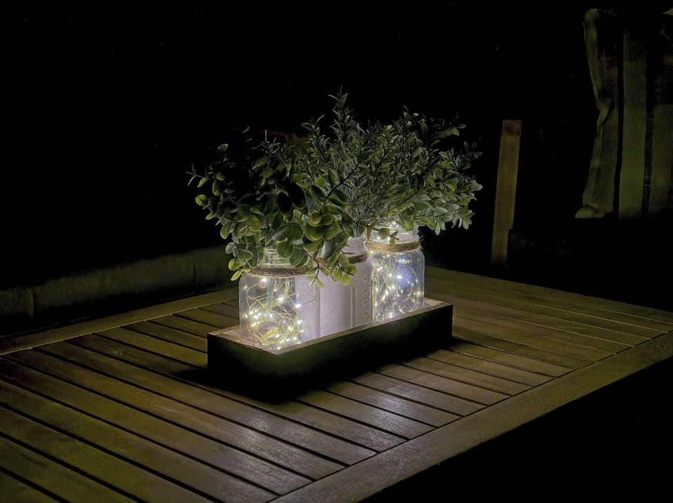 The details — mason jar with fairy lights and greenery on the deck coffee table. Thoughtful host touches throughout.