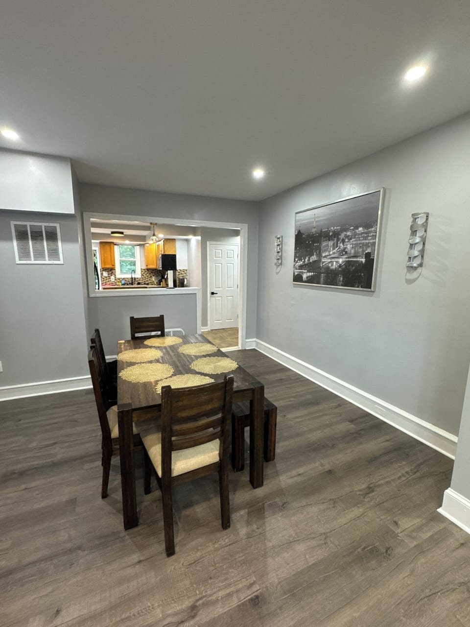 Charming dining area with wooden table, natural light, and kitchen view.