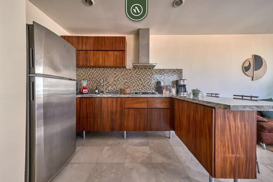 A spacious, fully equipped kitchen featuring sleek wood cabinetry and premium granite countertops. Includes a full-sized refrigerator and everything needed for gourmet vacation meals.