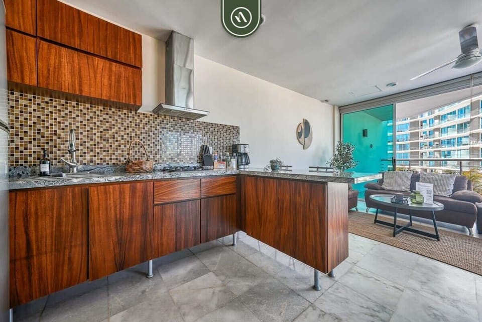 This sleek, wood-accented kitchen features premium granite countertops and modern appliances. The open-concept design allows you to cook while staying connected with guests in the lounge.