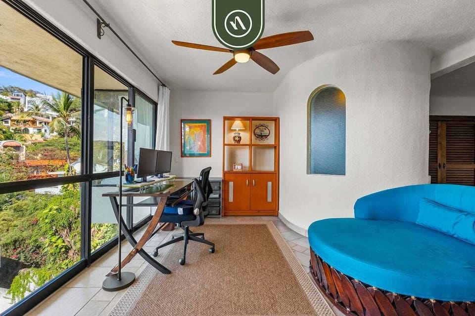 A bright workspace area featuring a desk setup right next to large windows that let in plenty of natural light.