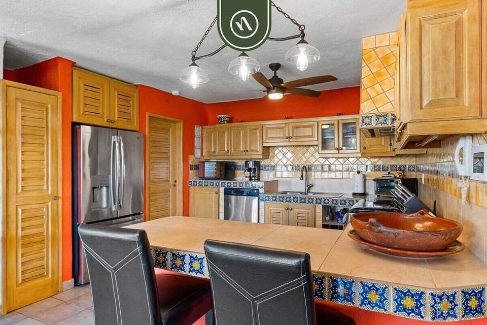 A spacious kitchen with traditional wood cabinetry, a central island, stainless steel appliances, and charming tile accents.