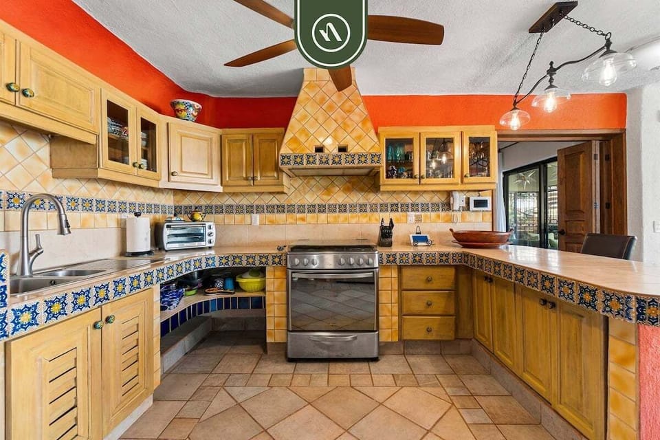 A detailed look at the kitchen, highlighting a stainless steel stove, a custom tiled range hood, and ample cabinet storage.