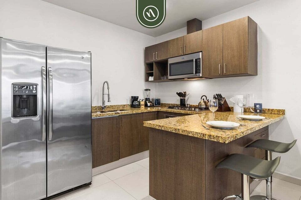 Sleek, fully equipped kitchen featuring stainless steel appliances, rich wood cabinetry, granite countertops, and a convenient breakfast bar.