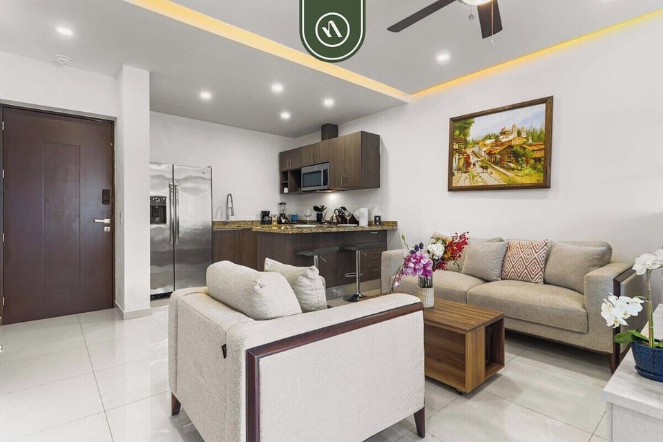 A bright, open-concept area seamlessly connecting the comfortable living room, featuring a contemporary beige sofa set, directly to the modern kitchen.