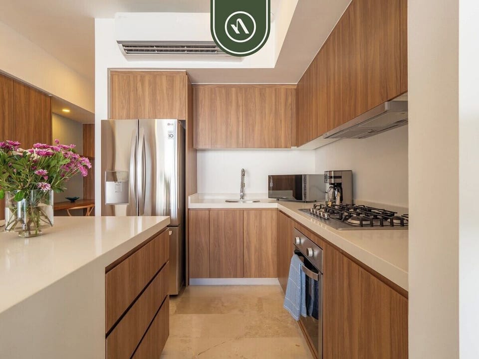 Fully equipped kitchen featuring stainless steel appliances, white countertops, and wood cabinetry.