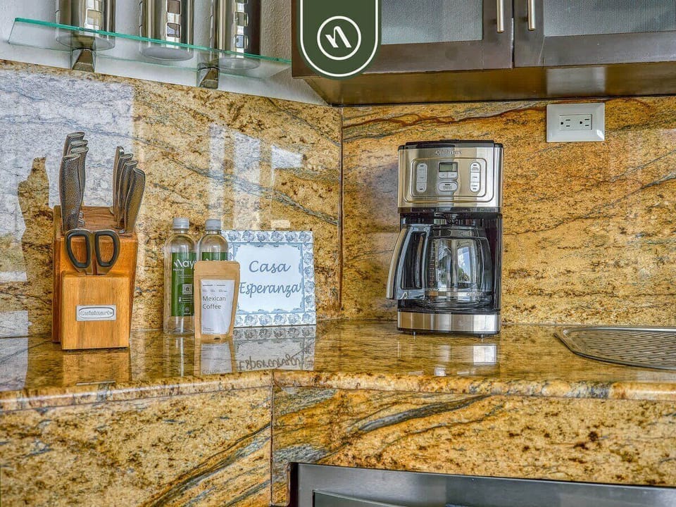 Detailed view of the rich granite backsplash highlighting a modern coffee maker, a professional knife block set, and decorative countertop accents.