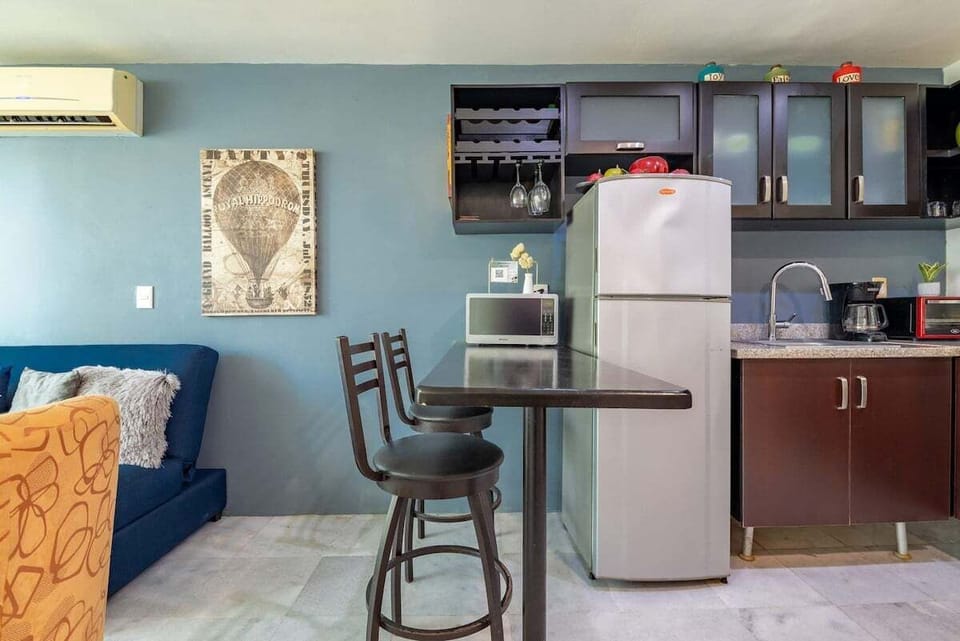 A close-up of the dining and prep area, featuring a sleek breakfast bar with high-top seating, dark wood cabinetry, and essential stainless steel appliances.