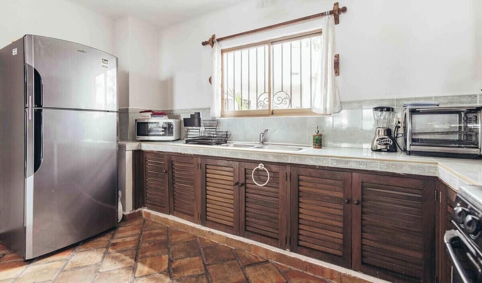 A functional kitchen area showcasing stainless steel appliances and classic dark wood slatted cabinetry.