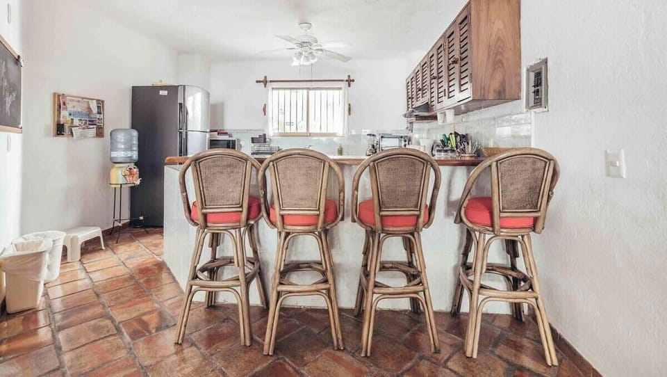 A cozy kitchen counter setup featuring four woven barstools with red cushions, perfect for casual dining.