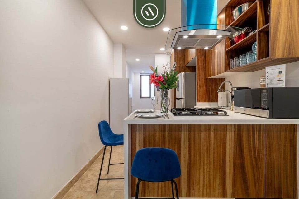 Pull up a seat at the stylish wooden breakfast bar. Featuring vibrant blue velvet stools and a sleek white countertop, this space is perfect for casual dining or enjoying your morning coffee in a bright, contemporary setting.