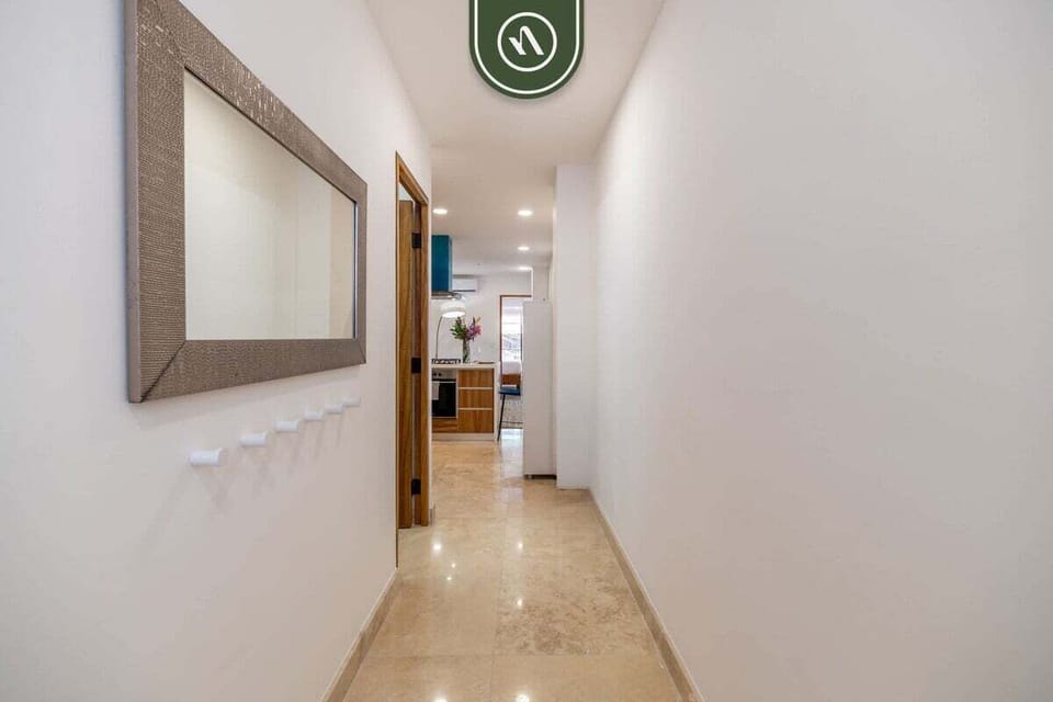 A clean and welcoming hallway with crisp white walls and modern lighting. The large wall mirror adds a sense of depth, leading you into the bright, open living spaces of this beautifully designed home.