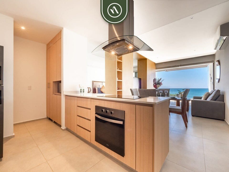 The sleek kitchen island features an integrated stove and overhead vent. Its open design allows for easy socializing with guests in the living and dining areas.