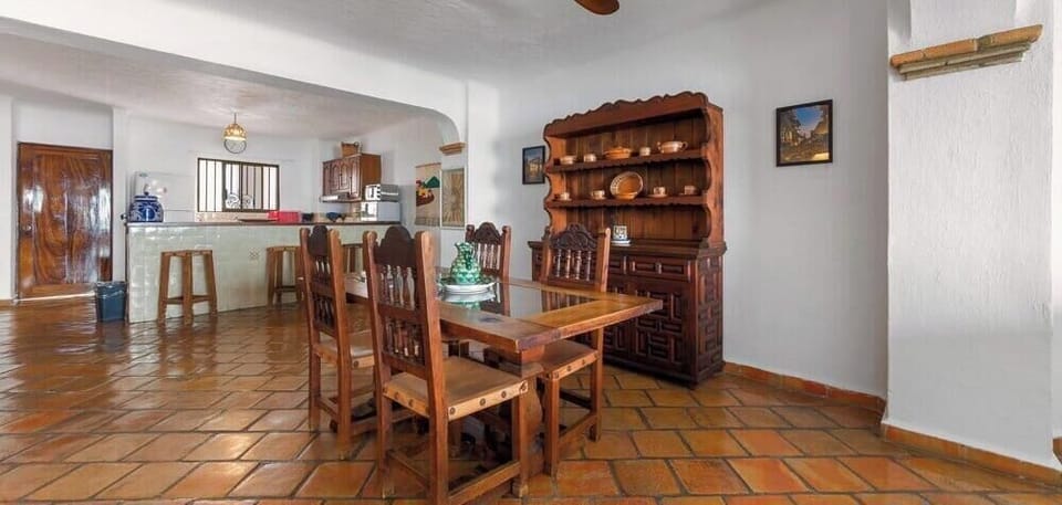 A rustic open dining space equipped with a carved wooden table set, situated across from a large classic wooden display hutch.