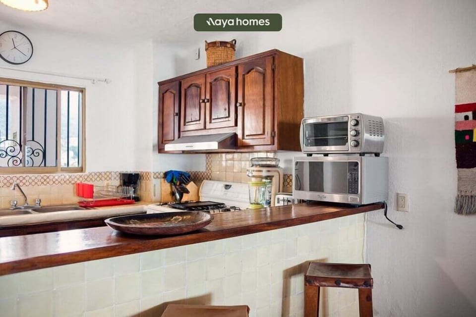 A compact kitchen setup showing upper wooden cabinets, a countertop toaster oven, and small appliances.
