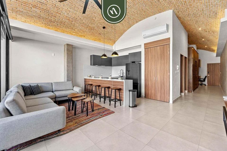 A wide-angle view highlighting the seamless flow between the comfortable lounge and the modern kitchen, all set under stunning vaulted brick ceilings.