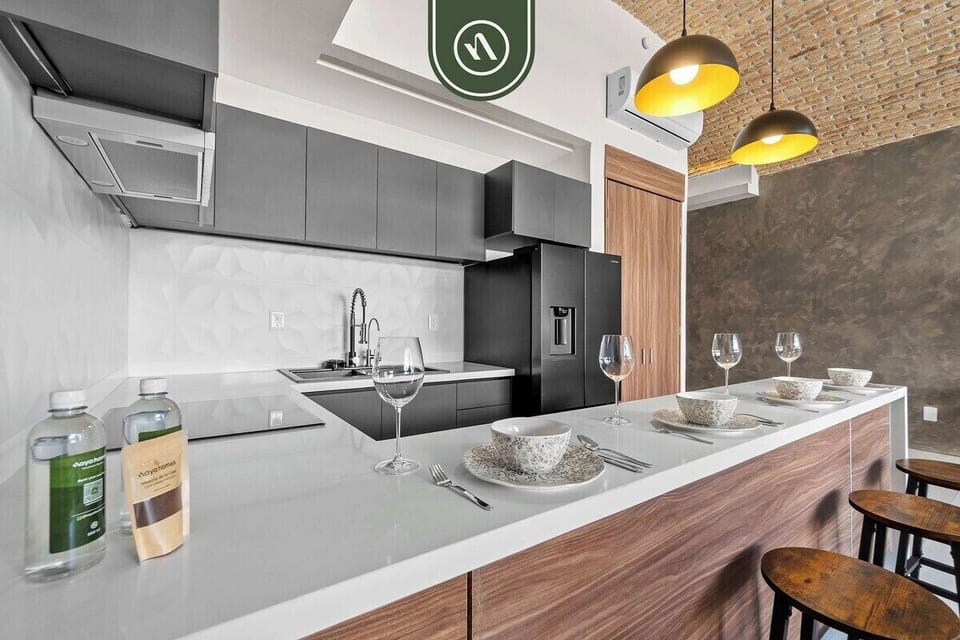 A sleek, fully-equipped kitchen with charcoal cabinetry, white stone countertops, and a spacious breakfast bar perfect for morning coffee.