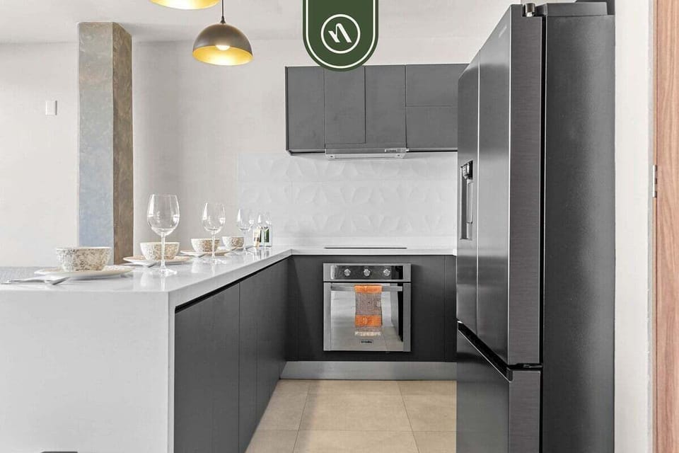 This shot showcases the sleek charcoal cabinetry, white countertops, and high-end stainless steel appliances.