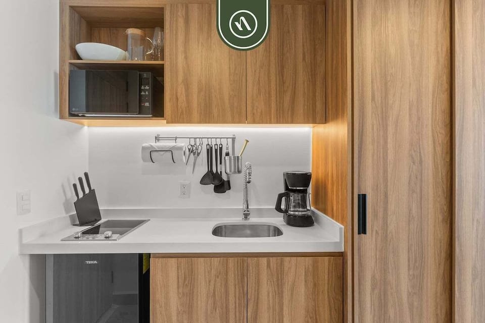 Compact, well-equipped kitchenette featuring modern cabinetry, sink, microwave, and essentials perfect for coffee, snacks, and simple meals