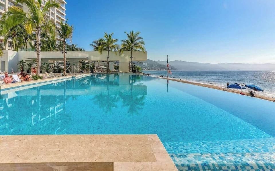 Stunning infinity pool overlooking Banderas Bay. Relax poolside with panoramic ocean views, lounge chairs, and direct beachfront scenery perfect for sunset swims and tropical relaxation in Puerto Vallarta.