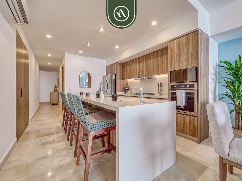 Spacious modern kitchen with a large island, bar seating, and stainless appliances. Perfect for preparing meals, morning coffee, or entertaining while enjoying your beachfront vacation stay.