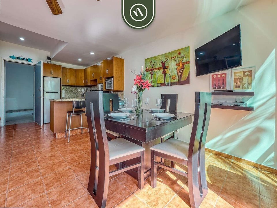 A view of the dining area and fully equipped kitchen. The dark wood table provides a sophisticated touch, while the open floor plan ensures the chef is always part of the conversation.