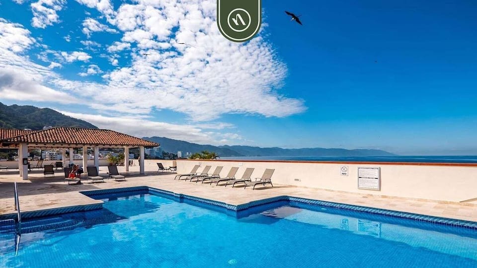 Oceanfront pool with lounge chairs and panoramic coastal scenery.