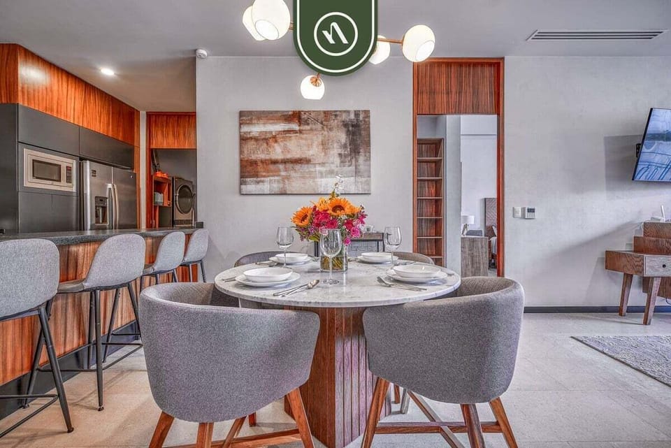 Beautiful round dining set looking directly into the contemporary kitchen area with its island barstools and warm wood accents.