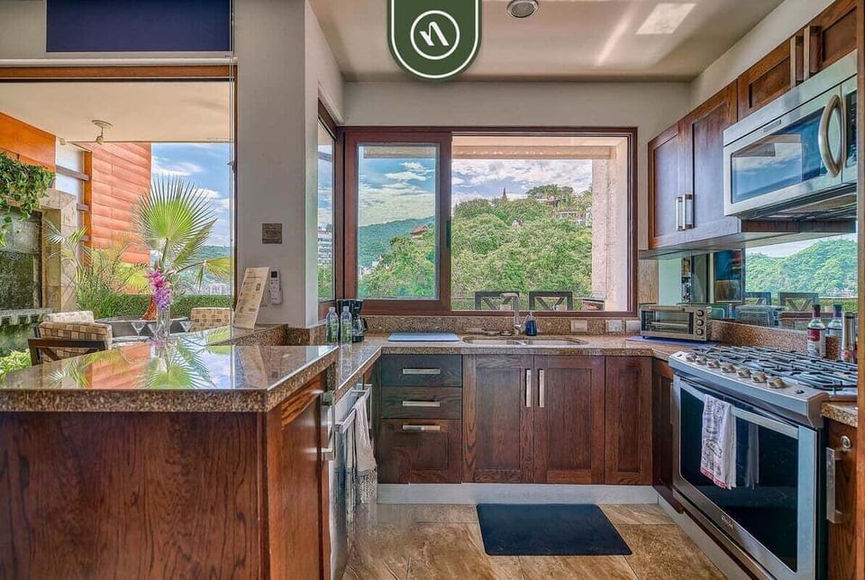 Prepare your favorite meals in this spacious kitchen featuring beautiful granite countertops, rich wood cabinetry, and a scenic window view.