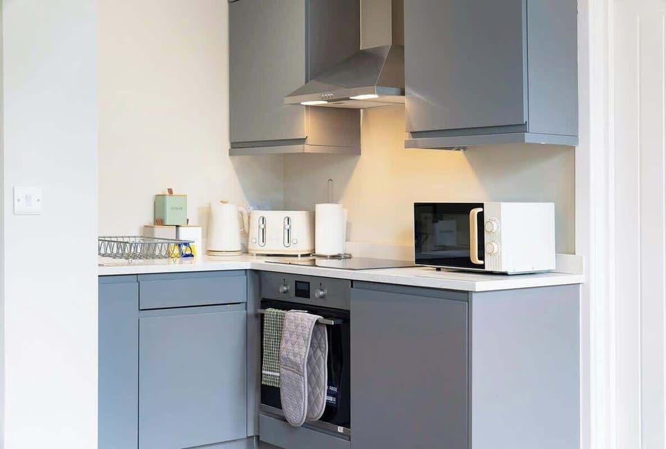 Kitchen equipped with all essentials, including an oven, fridge, microwave, toaster, kettle and full cookware set.
