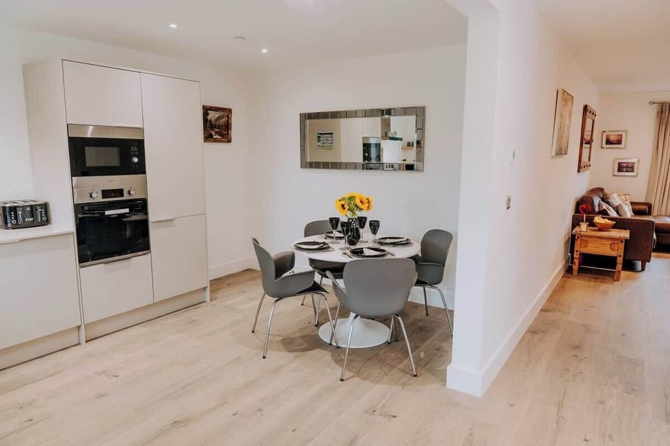 The open-plan kitchen flows seamlessly into a bright dining space set for four — perfect for relaxed meals or morning coffee. A high chair is available, ensuring even the smallest guests can dine in comfort at Cliftonville Cottage.