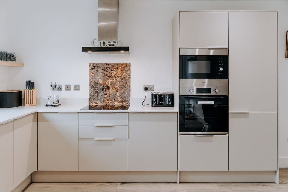 A sleek, high-end kitchen where modern design meets thoughtful detail — complete with integrated appliances, marble accents, and everything you need to cook, dine, and unwind in style at Cliftonville Cottage.