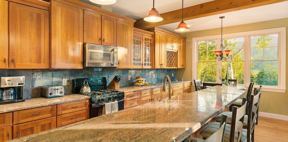 A spacious kitchen featuring stunning granite countertops and a breakfast bar with a view of Mt Snow