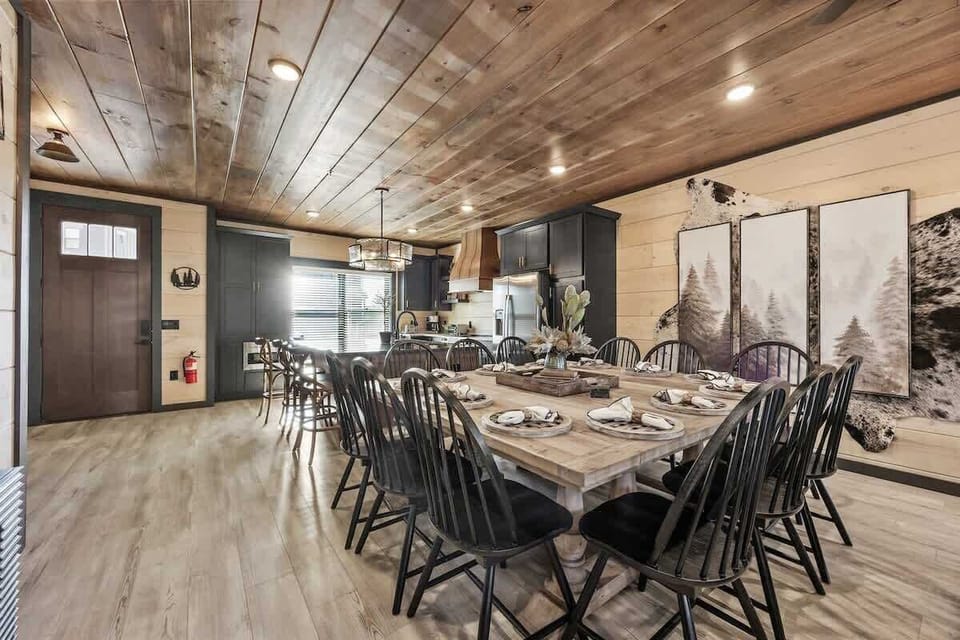 rustic dining area with a large wooden table and black chairs next to a modern kitchen