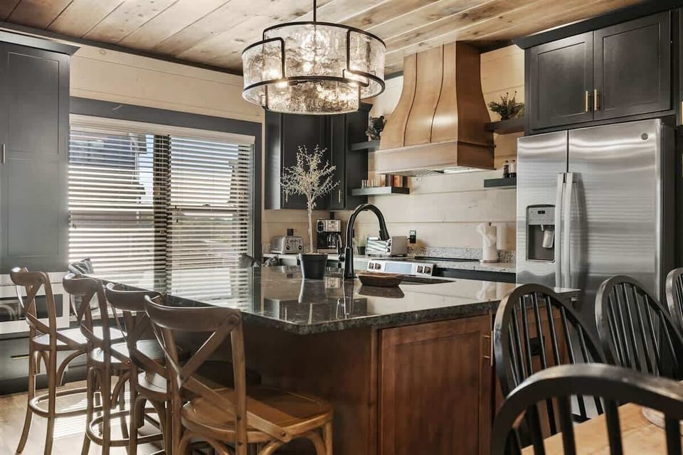 Modern kitchen with a large granite island and rustic wood accents for family-friendly gatherings.
