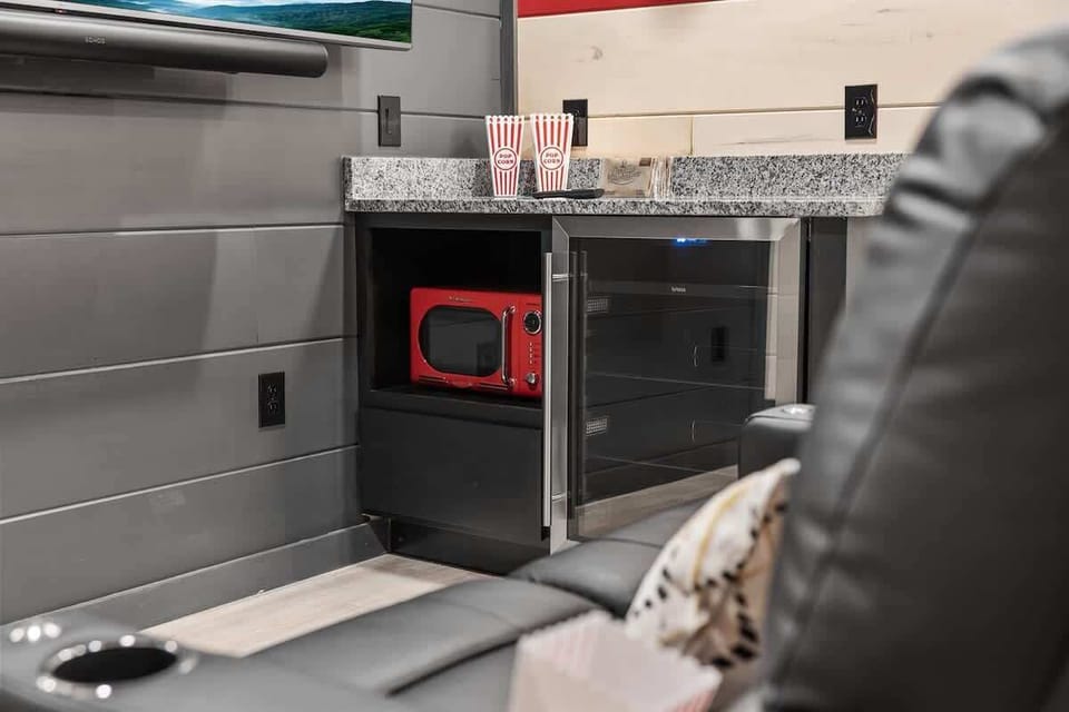 Modern entertainment area with a red microwave and mini fridge under a granite countertop.