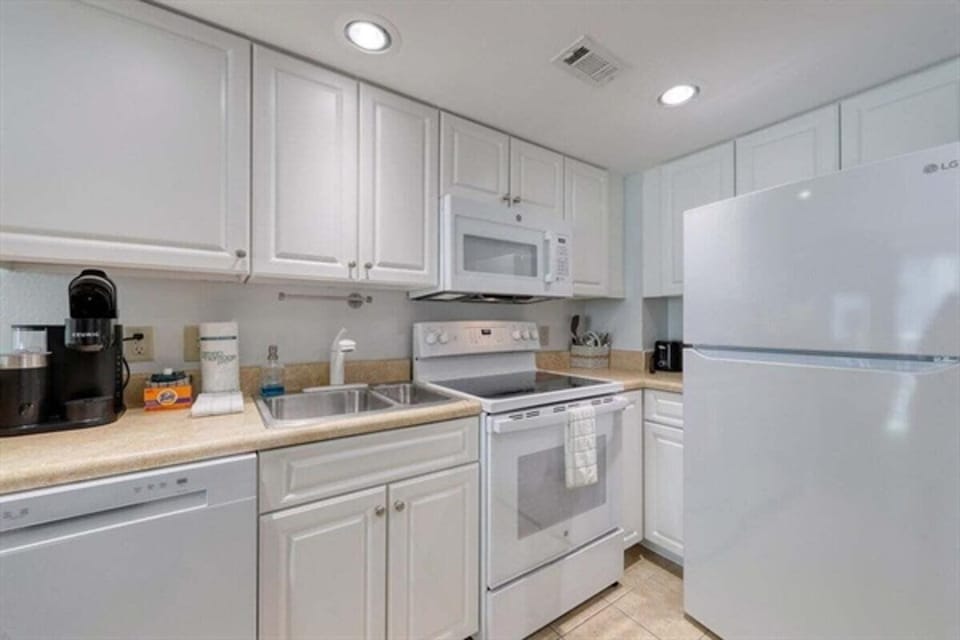Fully equipped kitchen with white cabinetry and full-size appliances