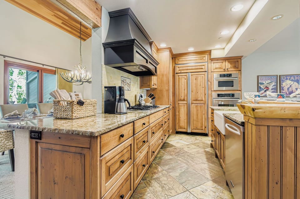 Prepare gourmet meals in this fully equipped kitchen featuring sleek granite countertops, rustic wood cabinetry, and a large farmhouse-style sink.