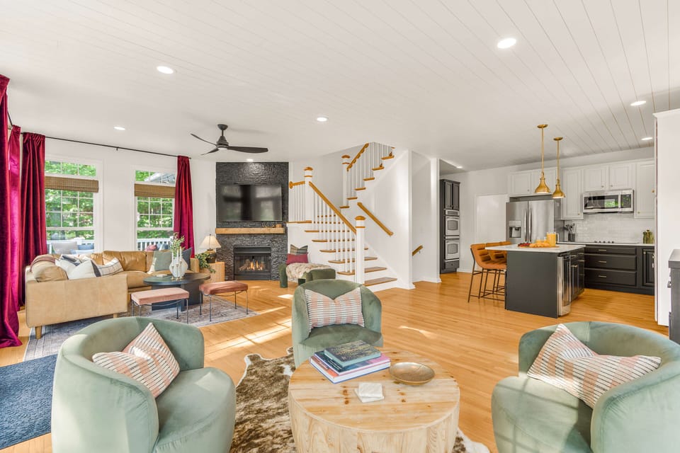 Relax in Palmer Summit's bright, open-concept living area—steps from both decks and the entertainment space below. Gather by the fireplace, enjoy the abundant natural light, savor mountain views, or unwind to your favorite vinyl on the record player.