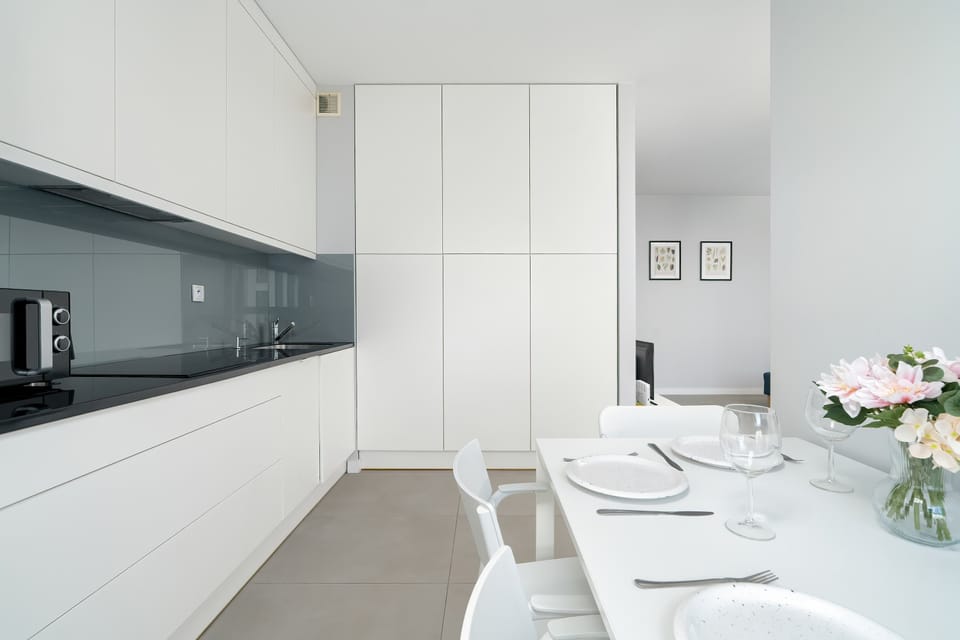 A contemporary white kitchen with clean lines and built-in appliances.