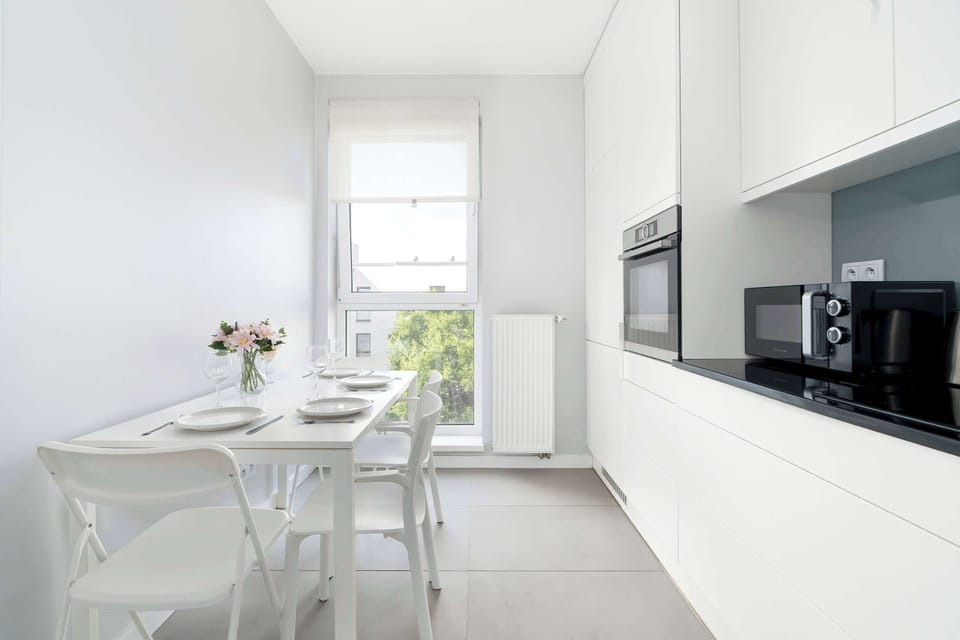 A stylish dining area connected to a sleek kitchen with white finishes.
