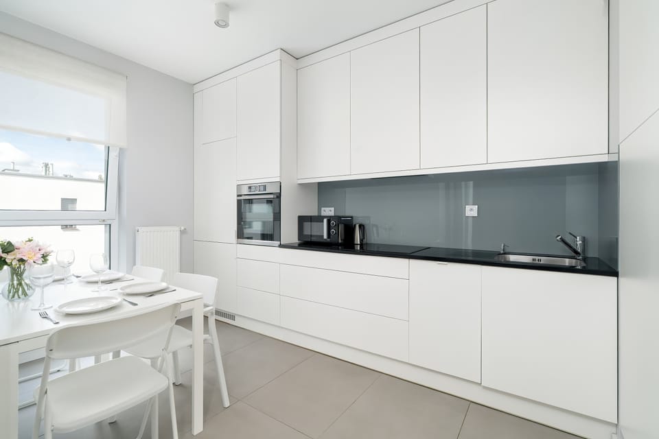 A stylish dining area connected to a sleek kitchen with white finishes.