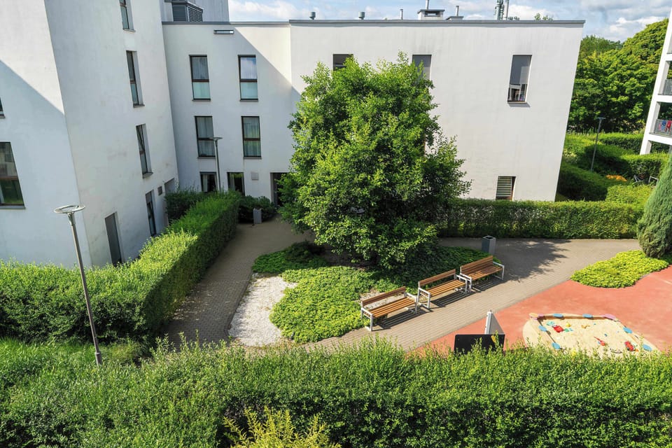 A small play area in a residential complex, surrounded by modern buildings and plants.