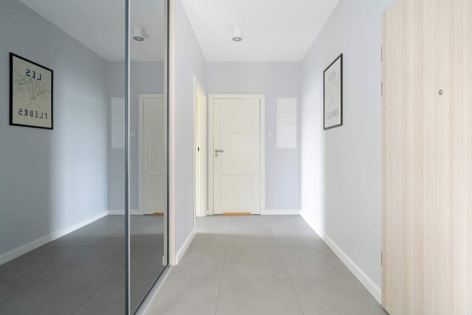 A hallway with a minimalistic design, light wood flooring, and bright lighting.